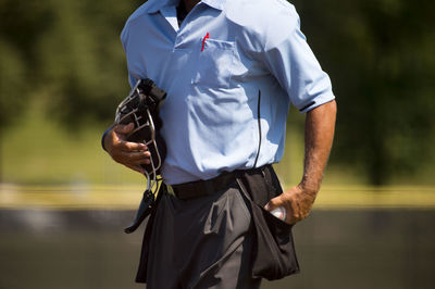 Midsection of referee with ball walking on field