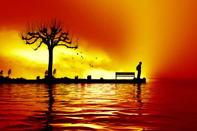 Silhouette tree by lake against sky during sunset