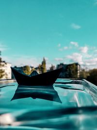 Close-up of paper boat against blue sky