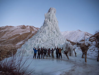 Group of people on snowcapped mountain against sky