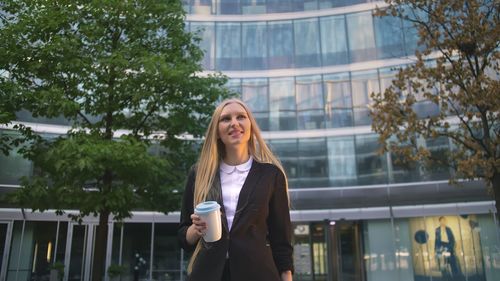 Woman standing by tree against building