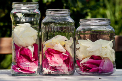 Rose petals in glass jars on table at yard