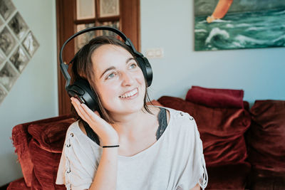 Young woman using mobile phone while sitting on sofa at home