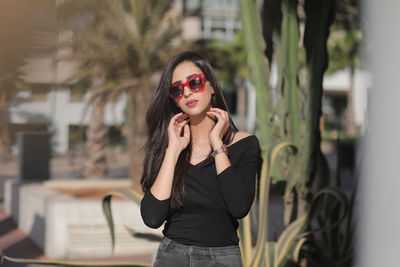 Portrait of young woman wearing sunglasses standing outdoors