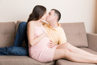 Rear view of friends sitting on sofa at home