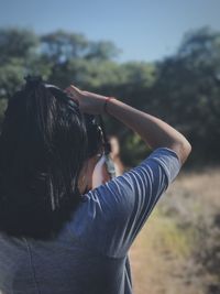 Rear view of woman photographing while standing on field