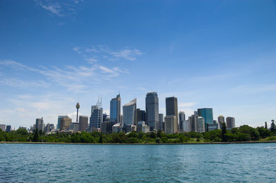 Modern buildings by river against sky in city