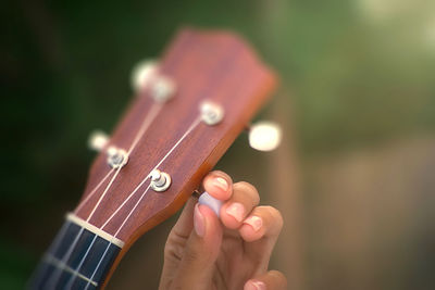 Cropped hand of woman adjusting guitar