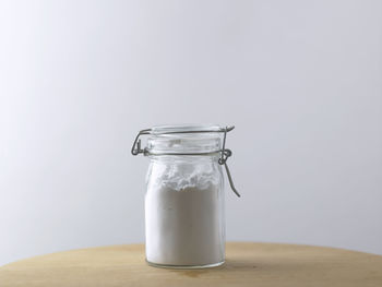 Close-up of glass jar on table against white background