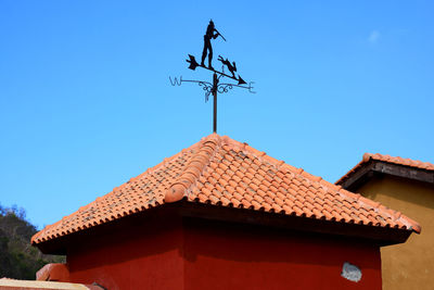 Low angle view of weather vane against building