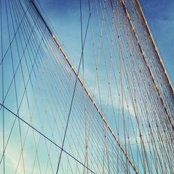 Low angle view of suspension bridge against blue sky