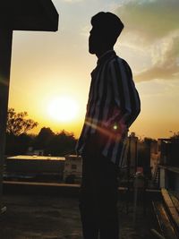 Side view of silhouette man standing against sky during sunset