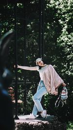 Happy young woman with head cocked holding pole in park