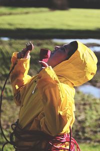 Side view of boy wearing raincoat rolled up with cables while standing outdoors