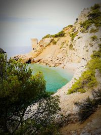 Scenic view of cliff by sea against sky