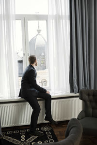 Businessman sitting on window sill looking at dome in hotel room