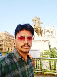 Portrait of young man standing against statue