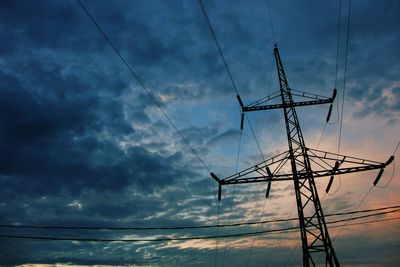 Low angle view of electricity pylon against cloudy sky