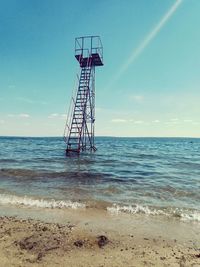 Rescue tower in sea against sky