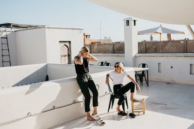 Friends relaxing on building terrace during sunny day