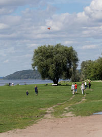 People at park by lake against sky