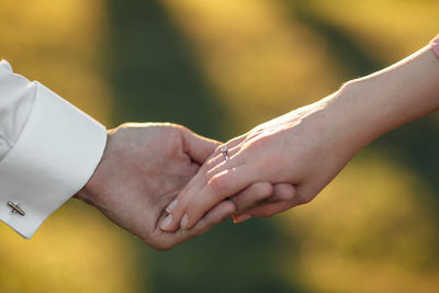 Cropped image of couple holding hands against blurred background