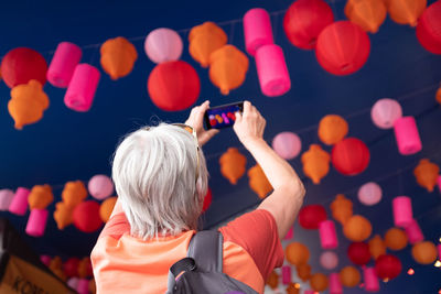 Rear view of woman photographing lanterns in sky
