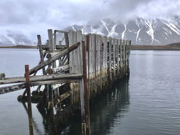 Wooden posts on pier over lake against sky