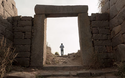 Rear view of man sitting on stone wall