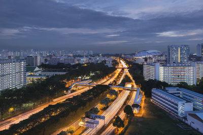 High angle view of city lit up against cloudy sky