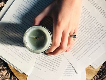 Woman holding lit candle over papers