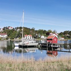 Sailboats moored on lake by building against sky