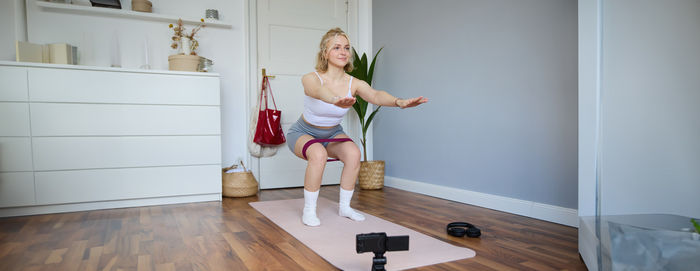 Full length of young woman exercising at home