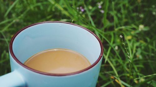Close-up of coffee in cup over grassy field