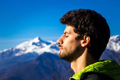 Portrait of young man looking away against sky