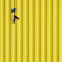 Security camera on patterned yellow wall