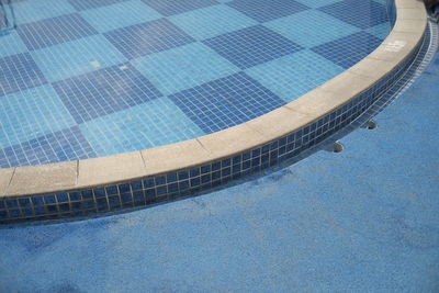 The poolside is blue, with clear water on a sunny day.
