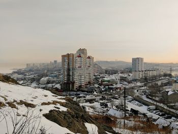 High angle view of snow covered buildings against sky during sunset