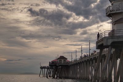 Pier over sea at huntington beach against cloudy sky during sunset