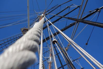 Low angle view of sailboat mast against blue sky