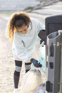Female volunteer throwing plastic waste in garbage can