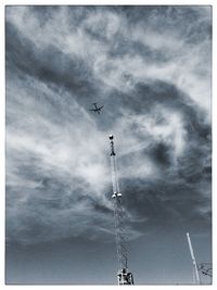 Low angle view of crane against cloudy sky