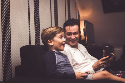 Father and son playing video game on sofa at home