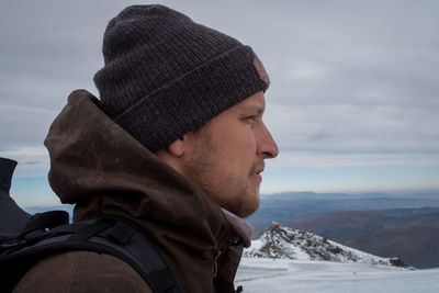 Close-up of man looking away against sky during winter