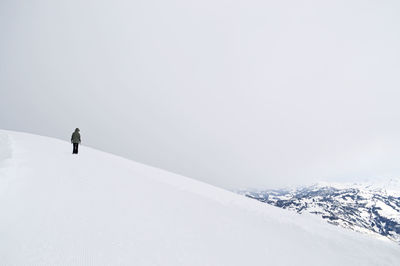 Man skiing on snowcapped mountain against clear sky