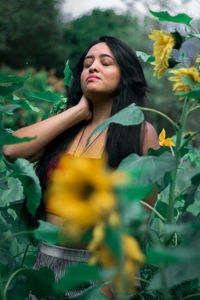 Beautiful woman with eyes closed standing amidst plants
