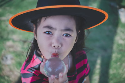 Portrait of girl wearing witch hat holding crystal ball