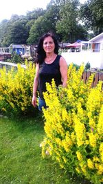 Portrait of smiling young woman against yellow flowers