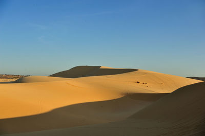 Scenic view of desert against blue sky