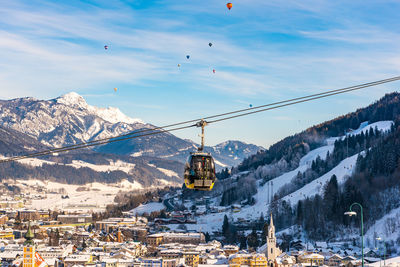 Overhead cable cars over snowcapped mountains against sky